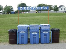 Photo of a special event recycling station with three recycling carts and a banner